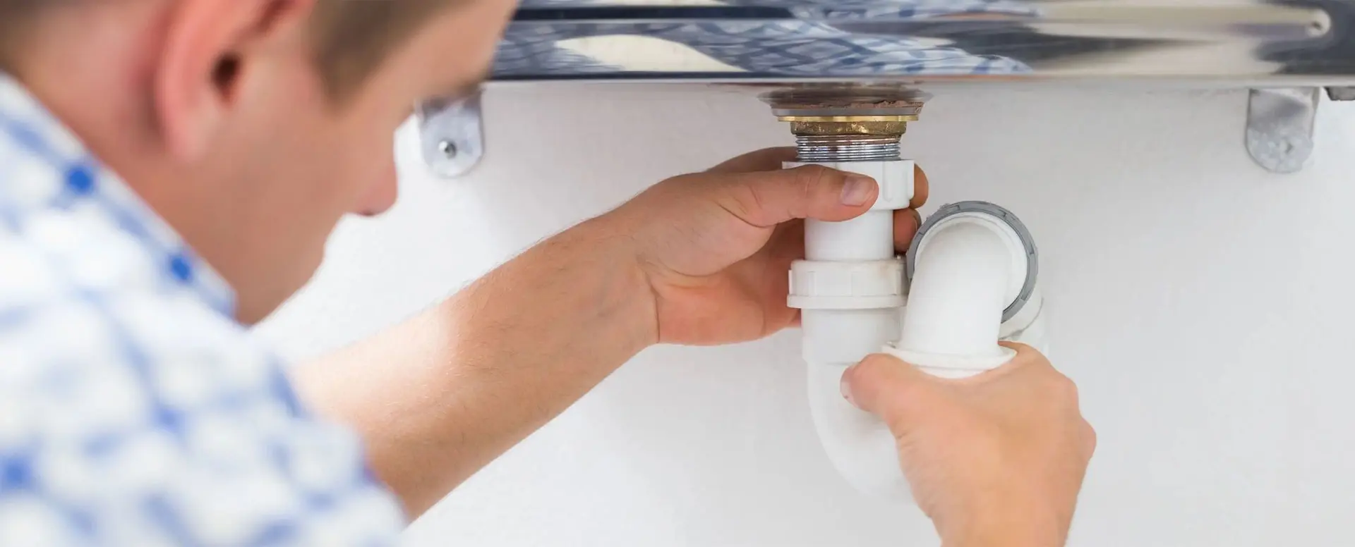 A person is fixing the faucet of a sink.