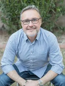 A man sitting on the ground wearing glasses.